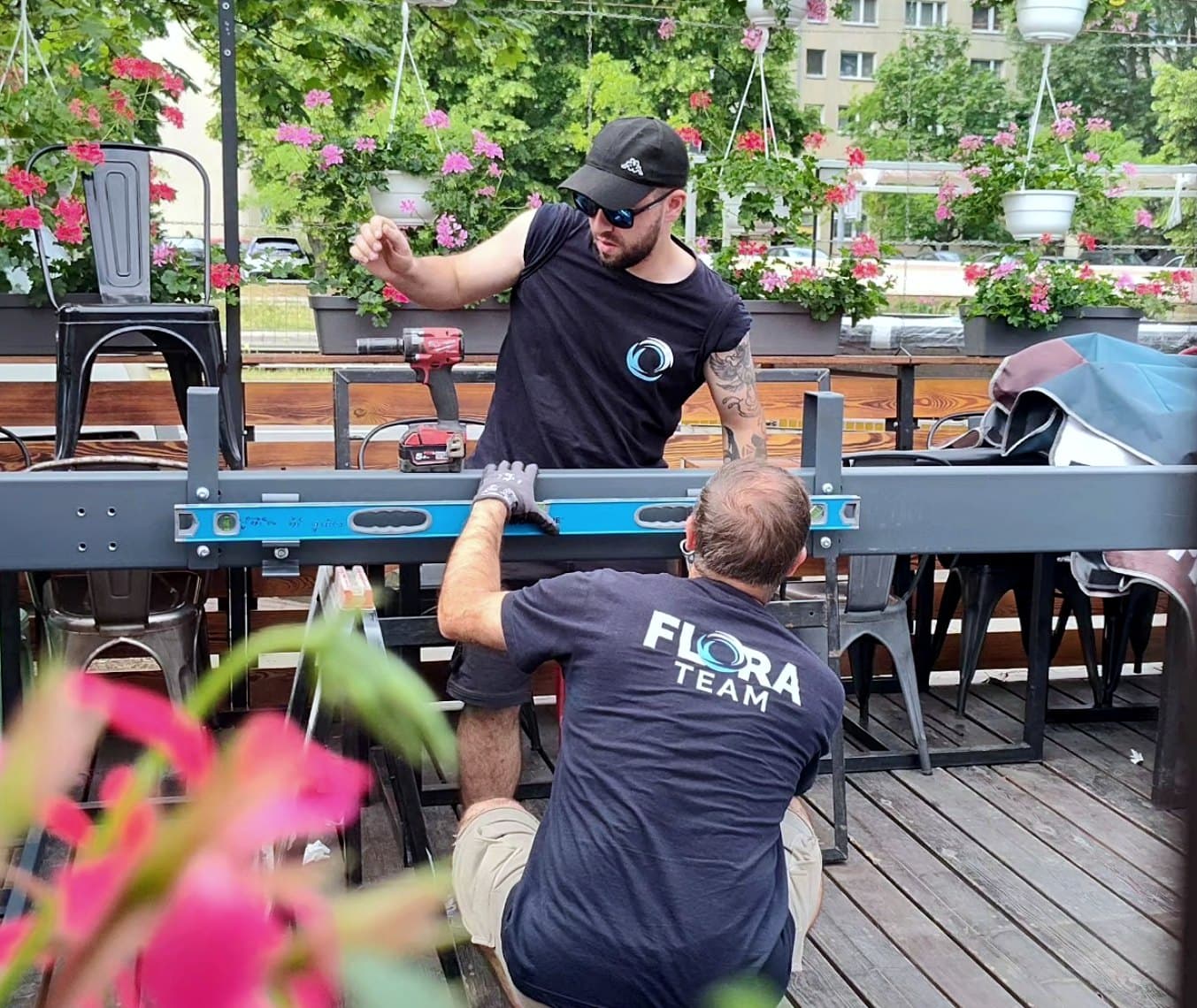 Dwóch montażystów Flora Team składa konstrukcję ogródka